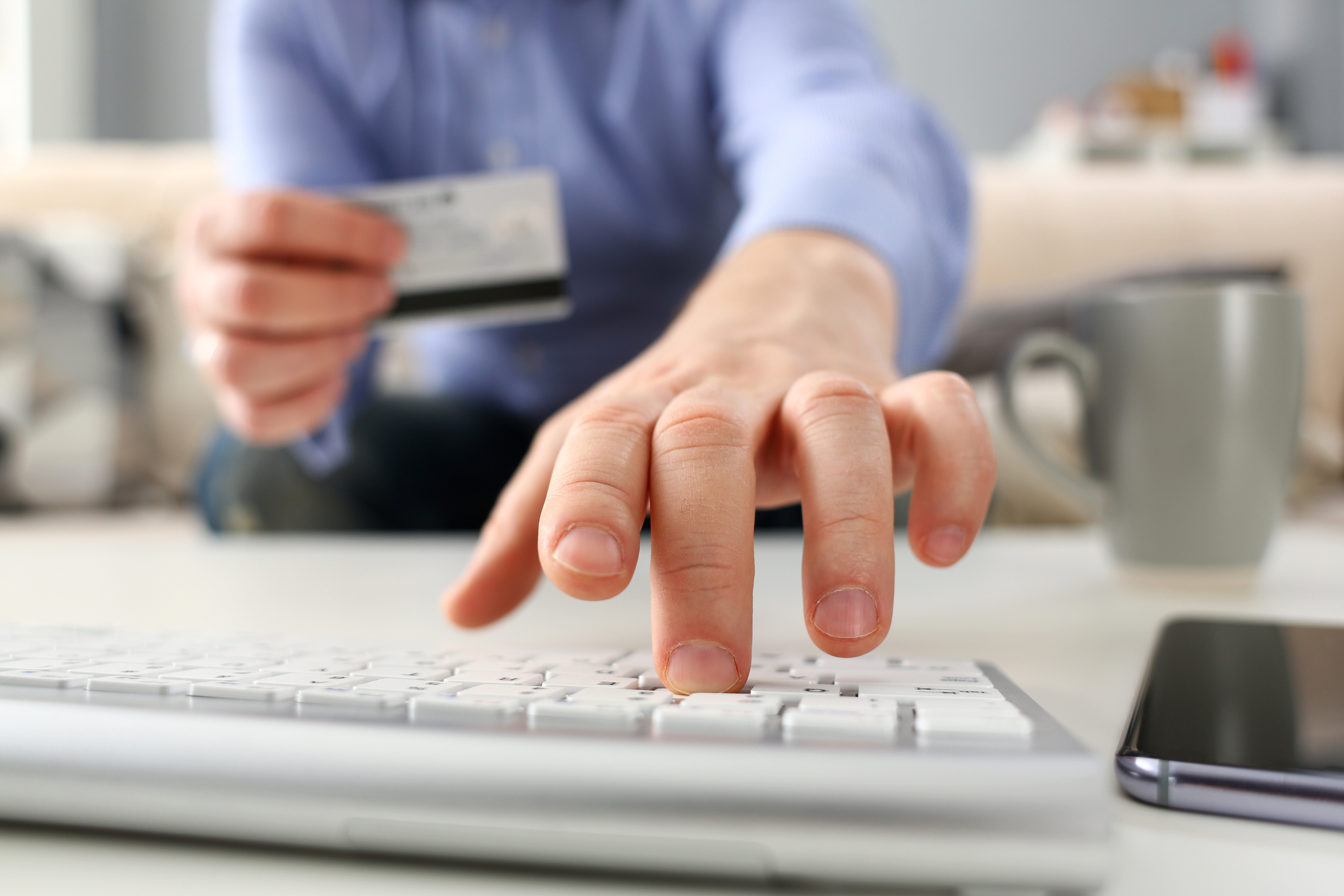 photo of a man typing on a keyboard and holding a bank card, problem gambling and gambling addiction